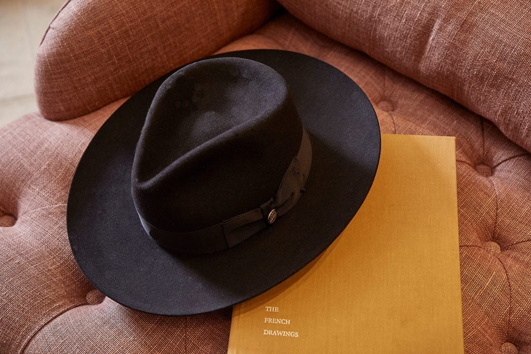 Stylish black hat on chair, resting on a book