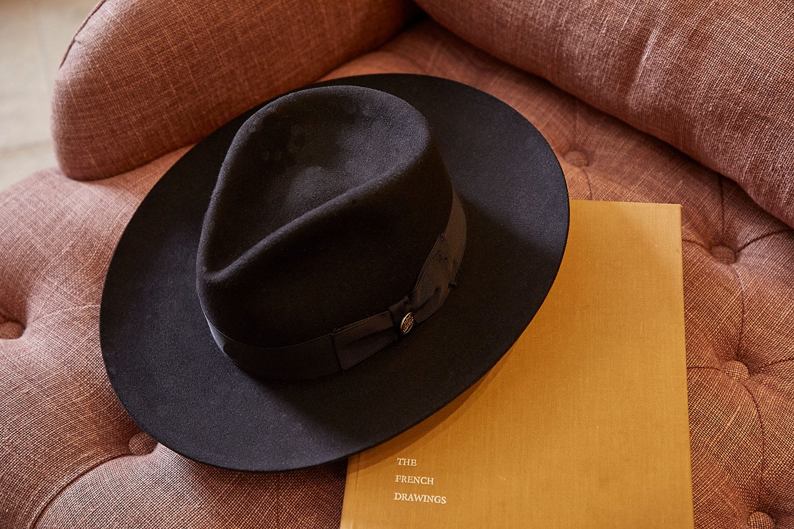 Stylish black hat on chair, resting on a book