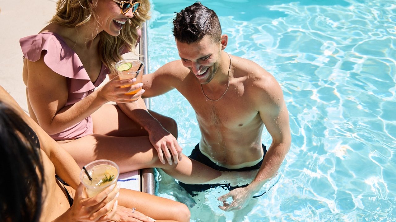 guests drinking cocktail at pool adolphus