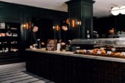 Barista ringing up a patron at a coffee counter with pastries