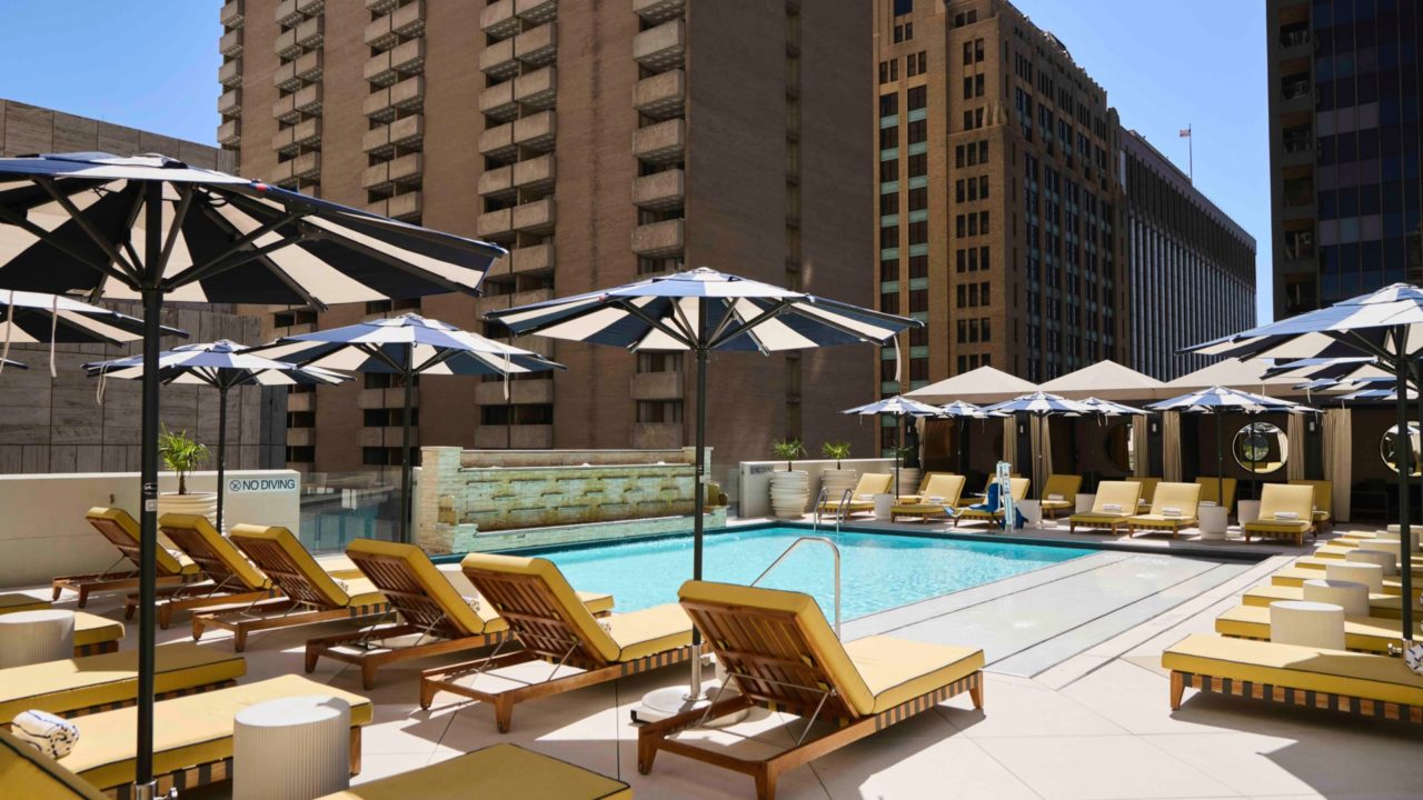 view of a pool and pool chairs with buildings in the background
