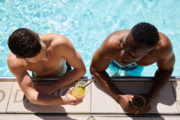 two men smiling with drinks in the pool