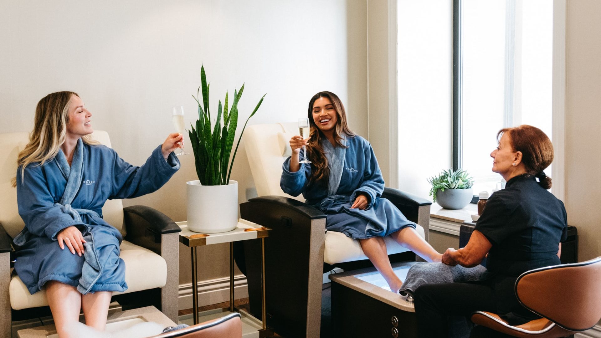 Two women in robes with champagne getting pedicures