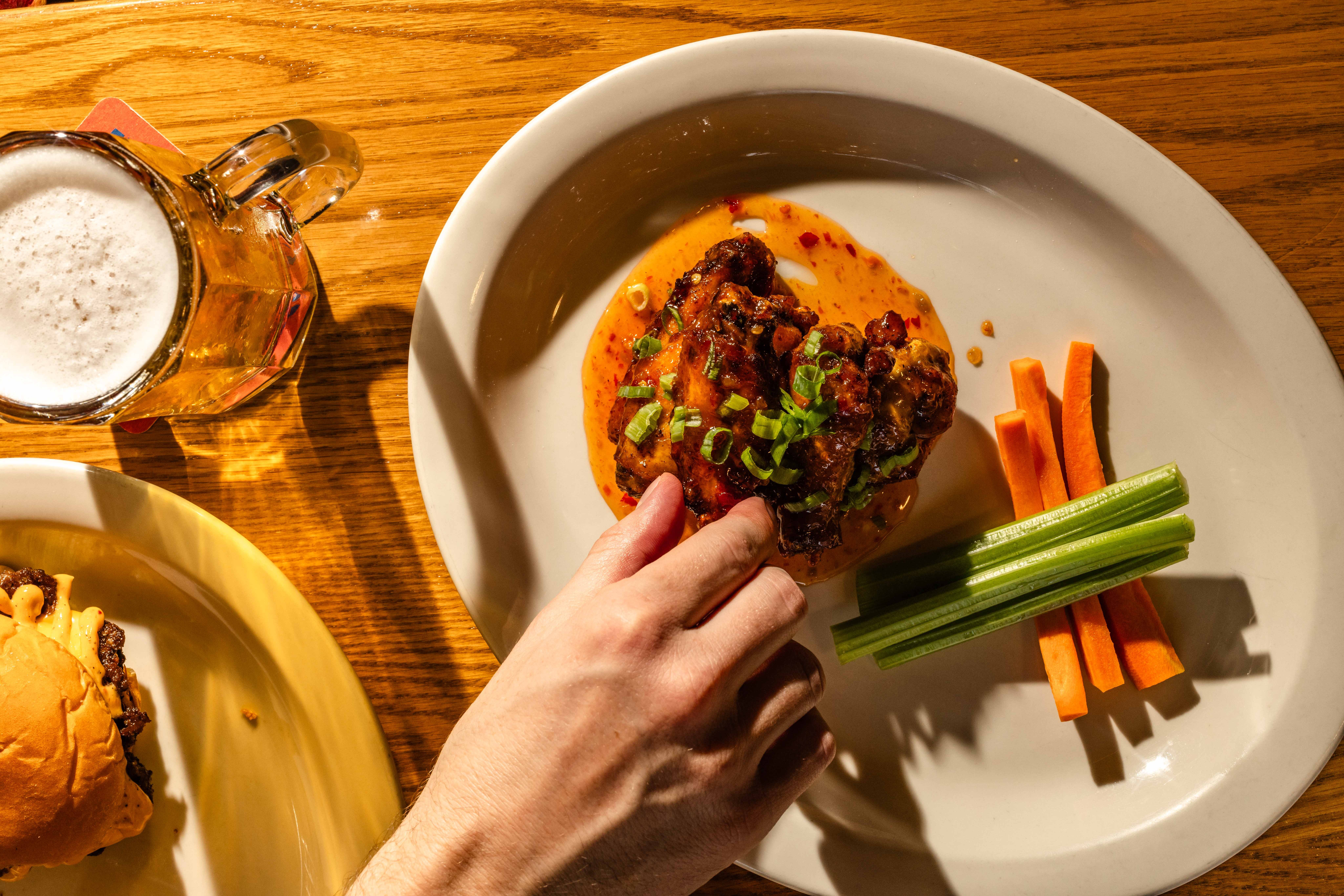 Chicken wings, celery, carrots and beer on a table