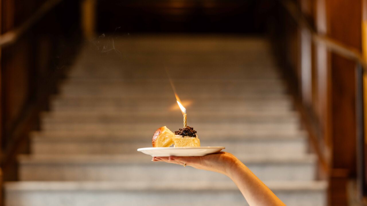 Caviar slider on a plate with a lit candle in front of the staircase