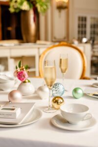 Champagne glasses and Christmas ornaments on a table with tea cups