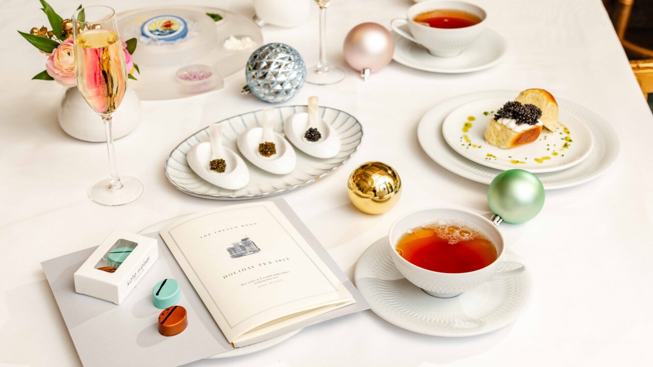 Tea cups, caviar flights, chocolate boxes and Champagne on a table near Christmas ornaments